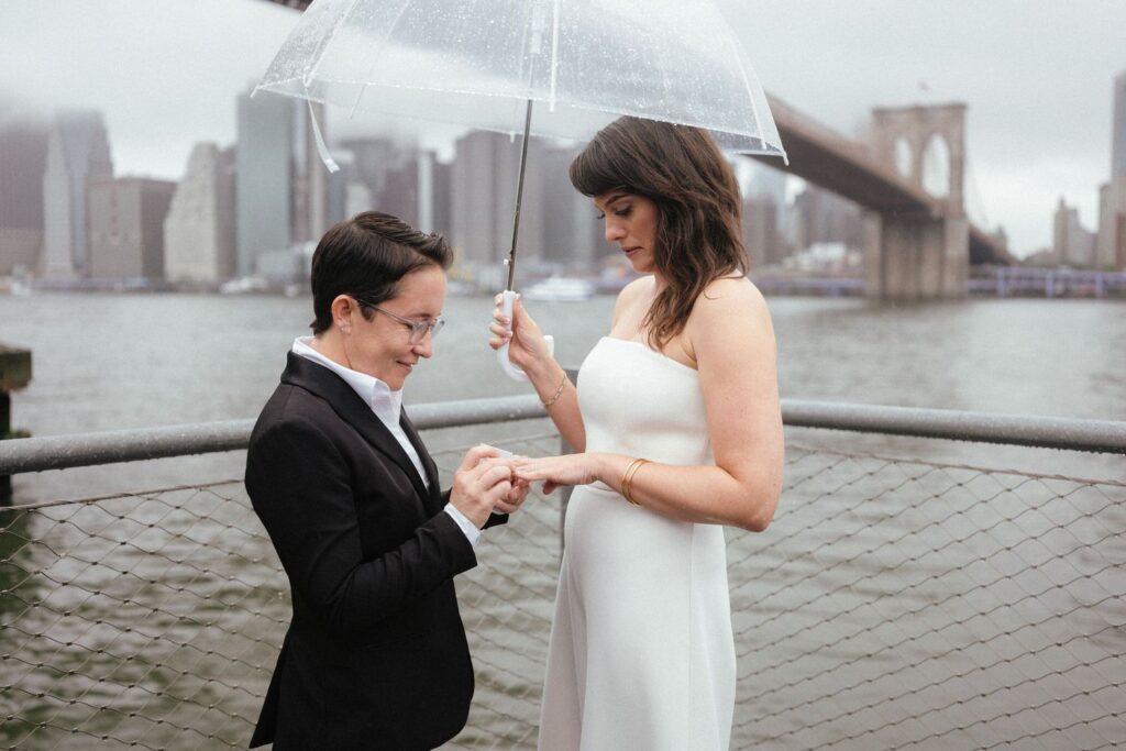 Bride holding umbrella at rainy outdoor Brooklyn wedding ceremony.